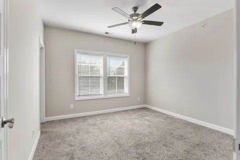 an empty room with windows and fan