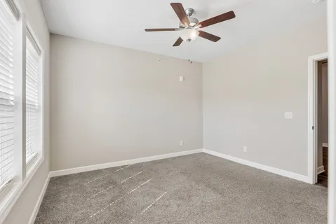 an empty room with a window and a fan