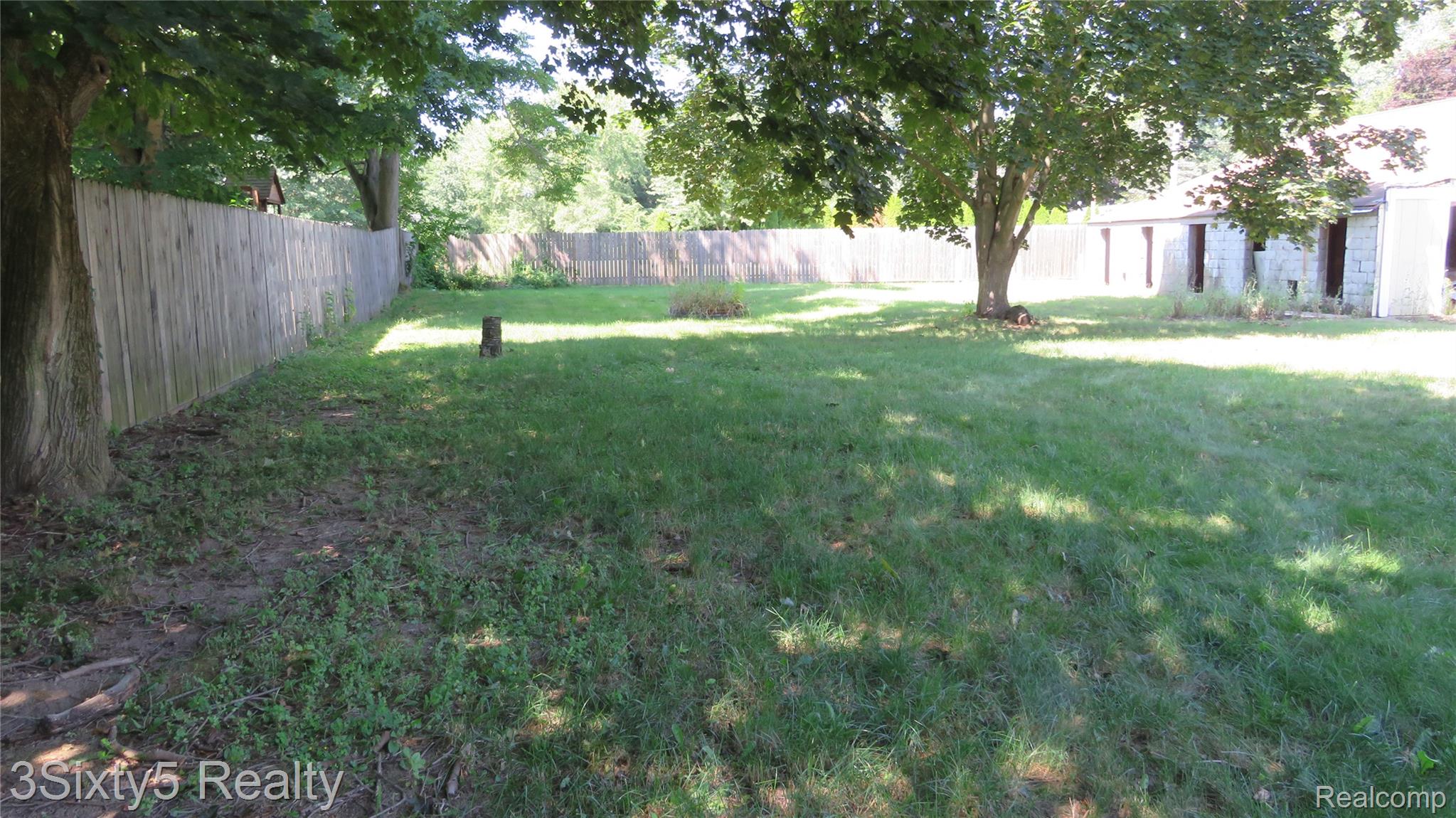 16558 Haggerty Road Belleville, MI 48111 - Photo 39 of 40 Expansive rear yard featuring a large grass area, mature trees, and a perimeter privacy fence
