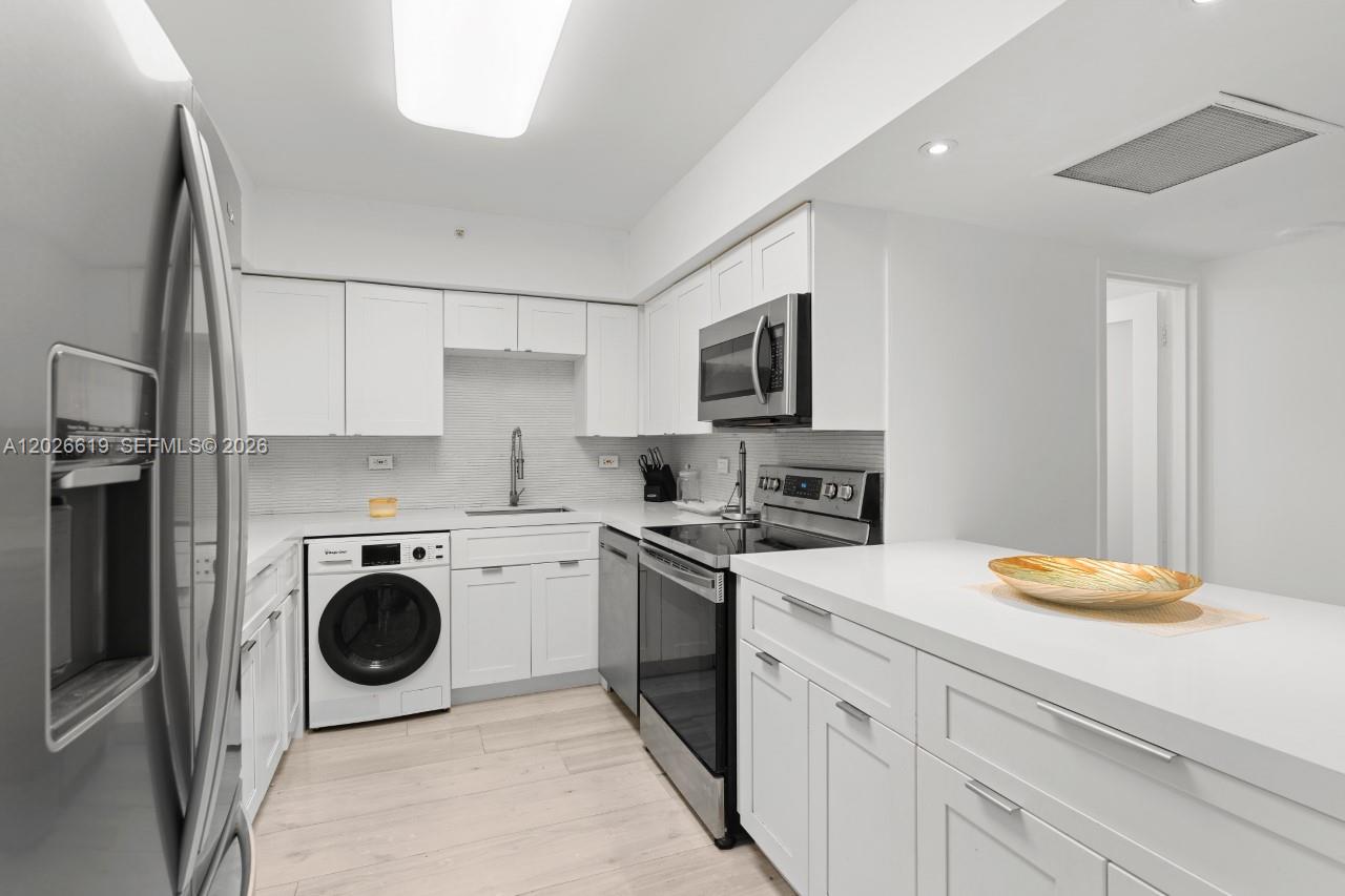 1500 Bay Road, Unit 1268S Miami Beach, FL 33139 - Photo 15 of 31 a kitchen with a sink a stove top oven and white kitchen