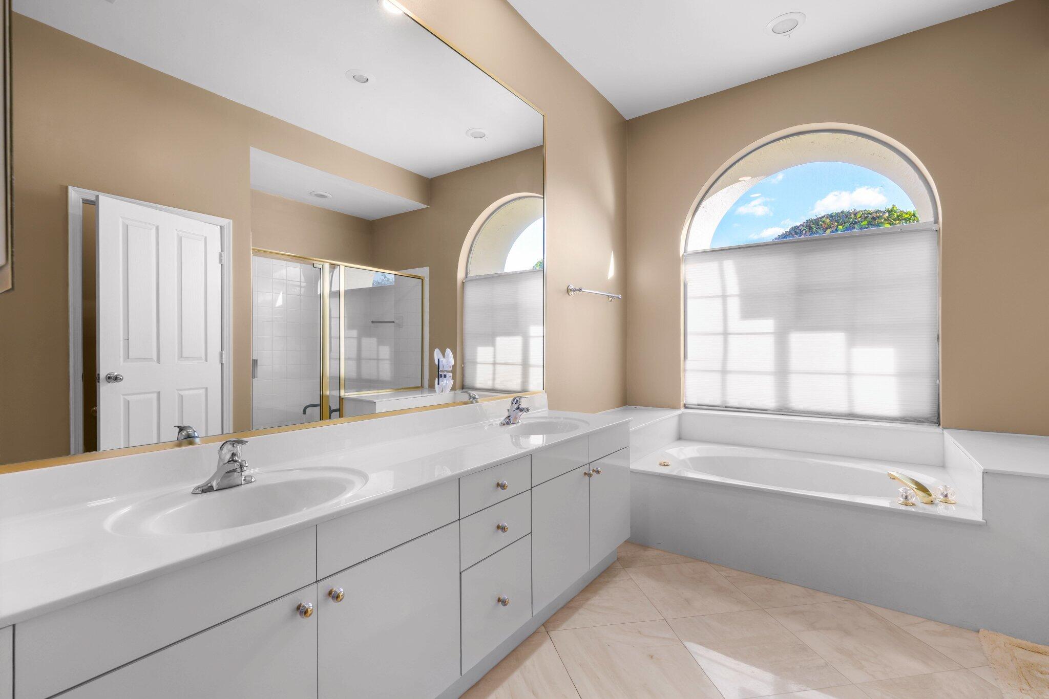 2595 Northwest 53rd Street Boca Raton, FL 33496 - Photo 11 of 48 a spacious bathroom with a double vanity sink a mirror a window and a bathtub
