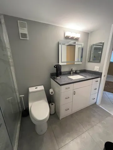 a bathroom with a granite countertop sink toilet and shower