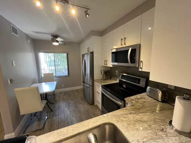 a kitchen with stainless steel appliances kitchen island granite countertop a refrigerator a stove a microwave oven a sink with island and chairs
