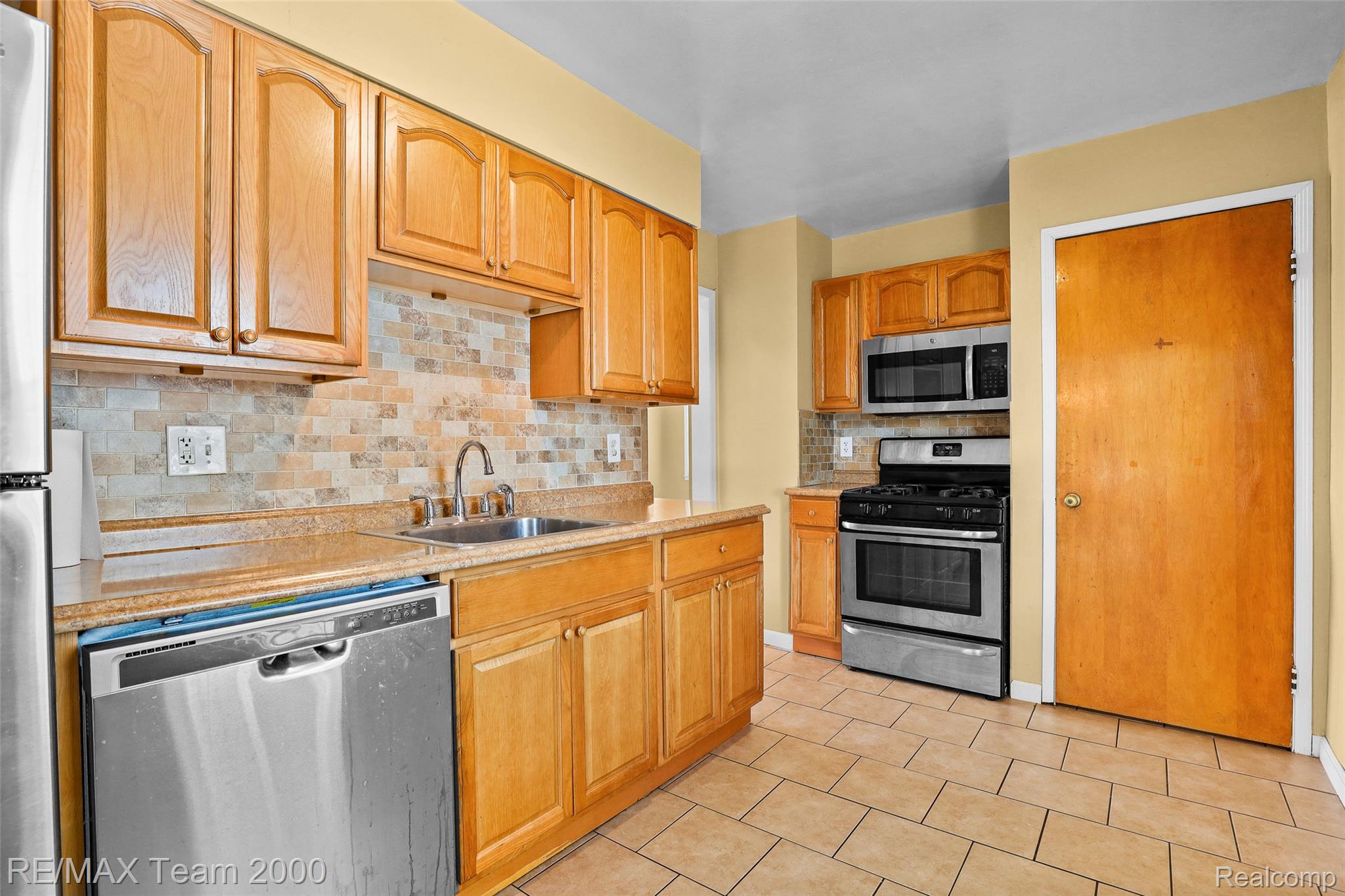 3130 Chestnut Street Dearborn, MI 48124 - Photo 8 of 30 Kitchen featuring light wood cabinetry, stone-look countertops, stainless steel appliances, and a tiled backsplash