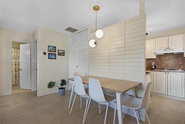a kitchen with stainless steel appliances granite countertop a dining table chairs and white cabinets