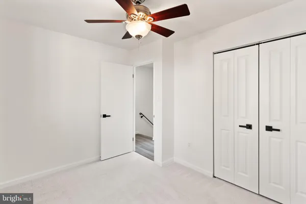 an empty room with closet and a chandelier fan