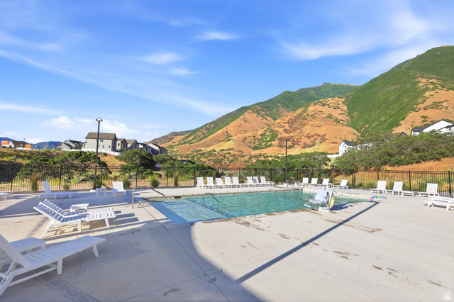4646 Alder Drive, Unit 223 Mapleton, UT 84664 - Photo 29 of 35 Community swimming pool with surrounding concrete deck, multiple lounge chairs, and a mountain backdrop
