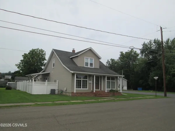 a front view of a house with a garden and trees