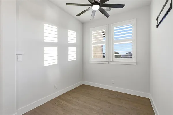 an empty room with windows and fan
