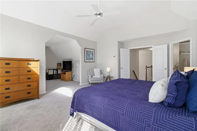 a spacious bedroom with a bed a dresser and a chandelier