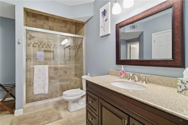 a bathroom with a granite countertop sink a toilet a mirror and shower