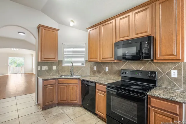 a kitchen with granite countertop a stove sink and microwave