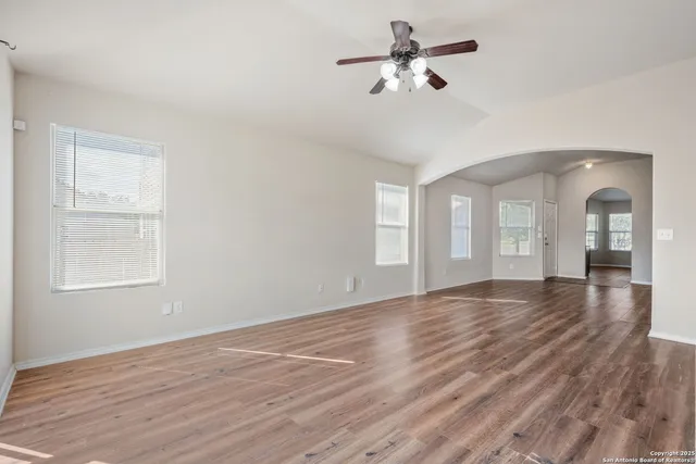 a view of empty room with wooden floor and fan