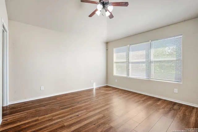a view of an empty room with wooden floor and a window