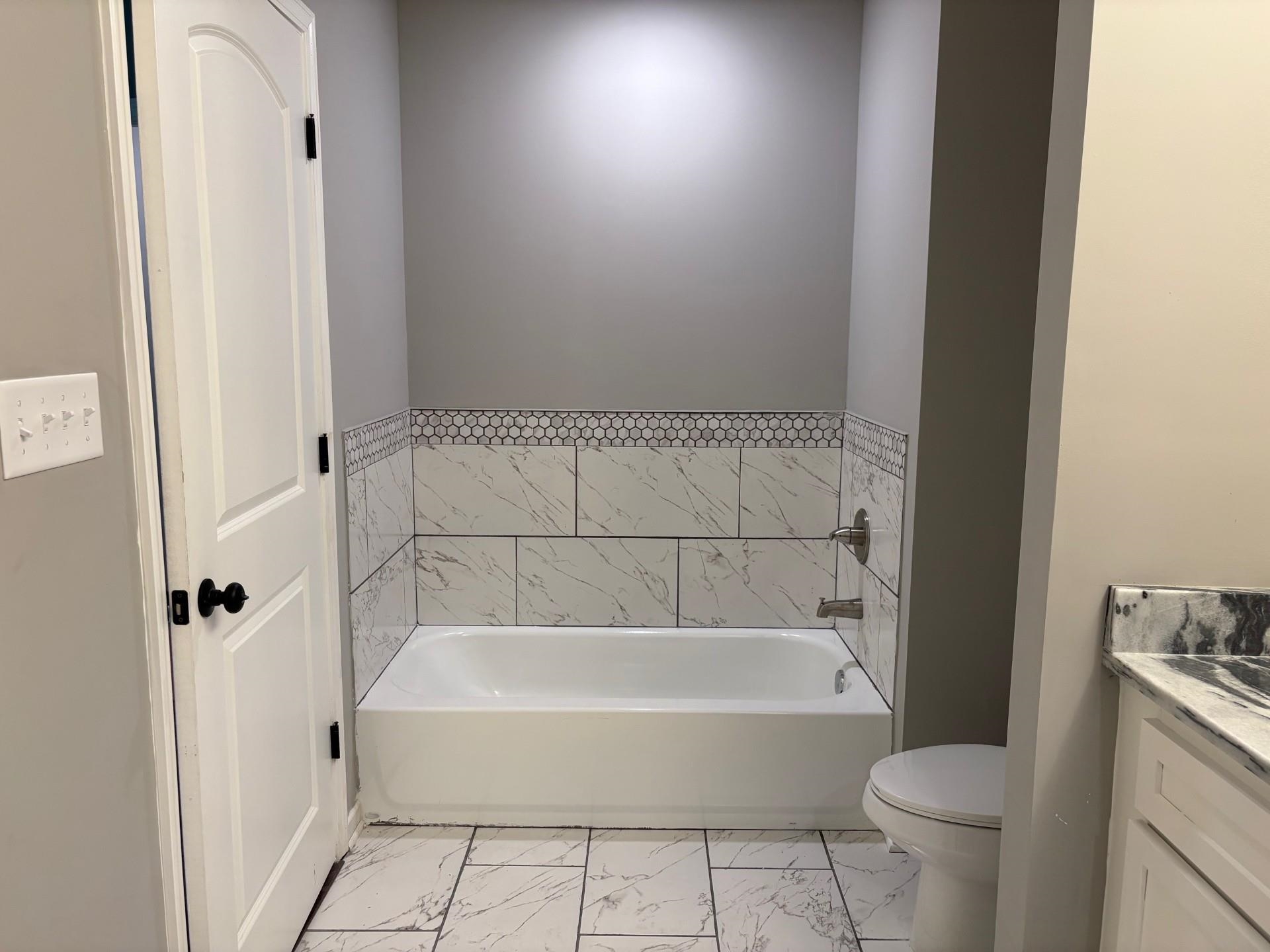 3701 Whittier Road Memphis, TN 38108 - Photo 12 of 13 Bathroom featuring vanity, marble look tile flooring, and a garden tub