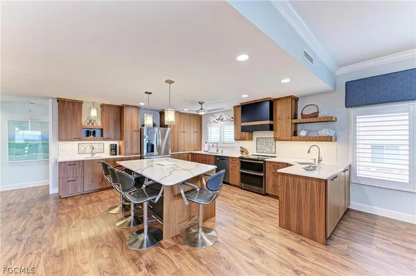 a kitchen with stainless steel appliances kitchen island granite countertop a table chairs and a refrigerator