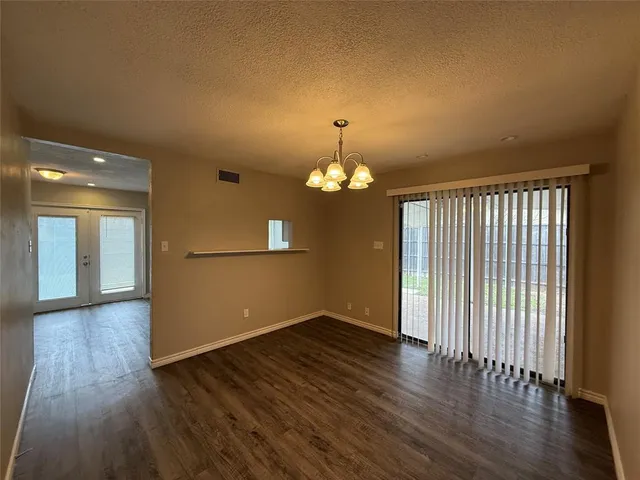 an empty room with wooden floor chandelier and windows