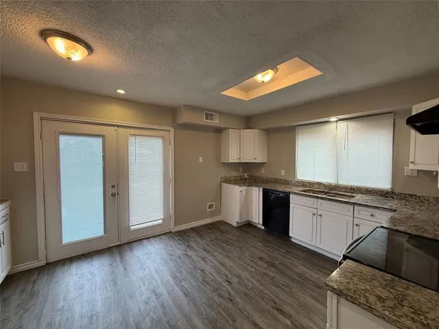 a large kitchen with granite countertop a large counter top space and stainless steel appliances