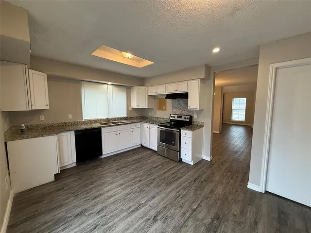 a kitchen with granite countertop a stove top oven and cabinets