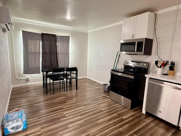 a kitchen with stainless steel appliances wooden floor and a refrigerator