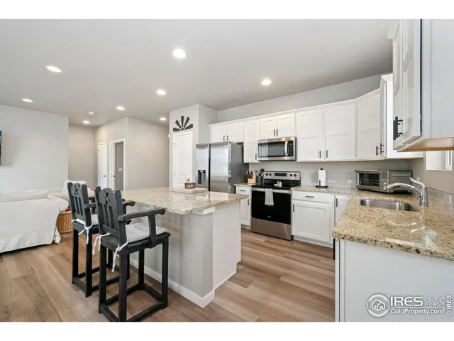a kitchen with stainless steel appliances granite countertop wooden cabinets a sink a stove a dining table and chairs