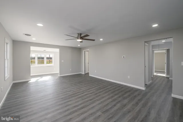 a view of an empty room with window and wooden floor