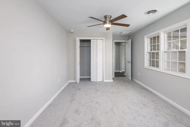 an empty room with windows and fan