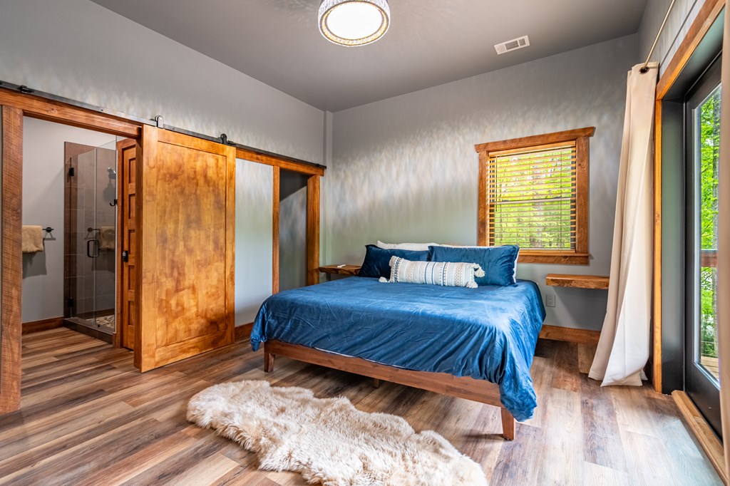 1220 Sunset Road Epworth, GA 30541 - Photo 30 of 46 a bedroom with a bed and a large window with wooden floor