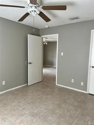 a view of an empty room and chandelier fan