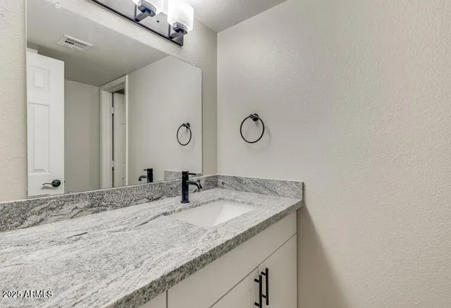 a bathroom with a granite countertop sink and a mirror