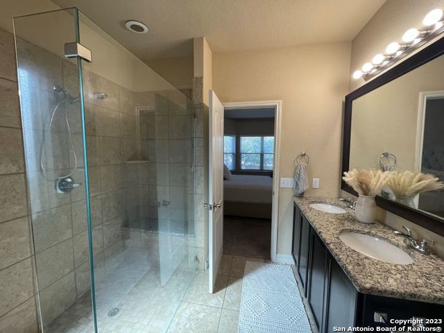 12310 Coal Mine Rise San Antonio, TX 78245 - Photo 6 of 19 a en suite bathroom with a granite countertop sink and shower