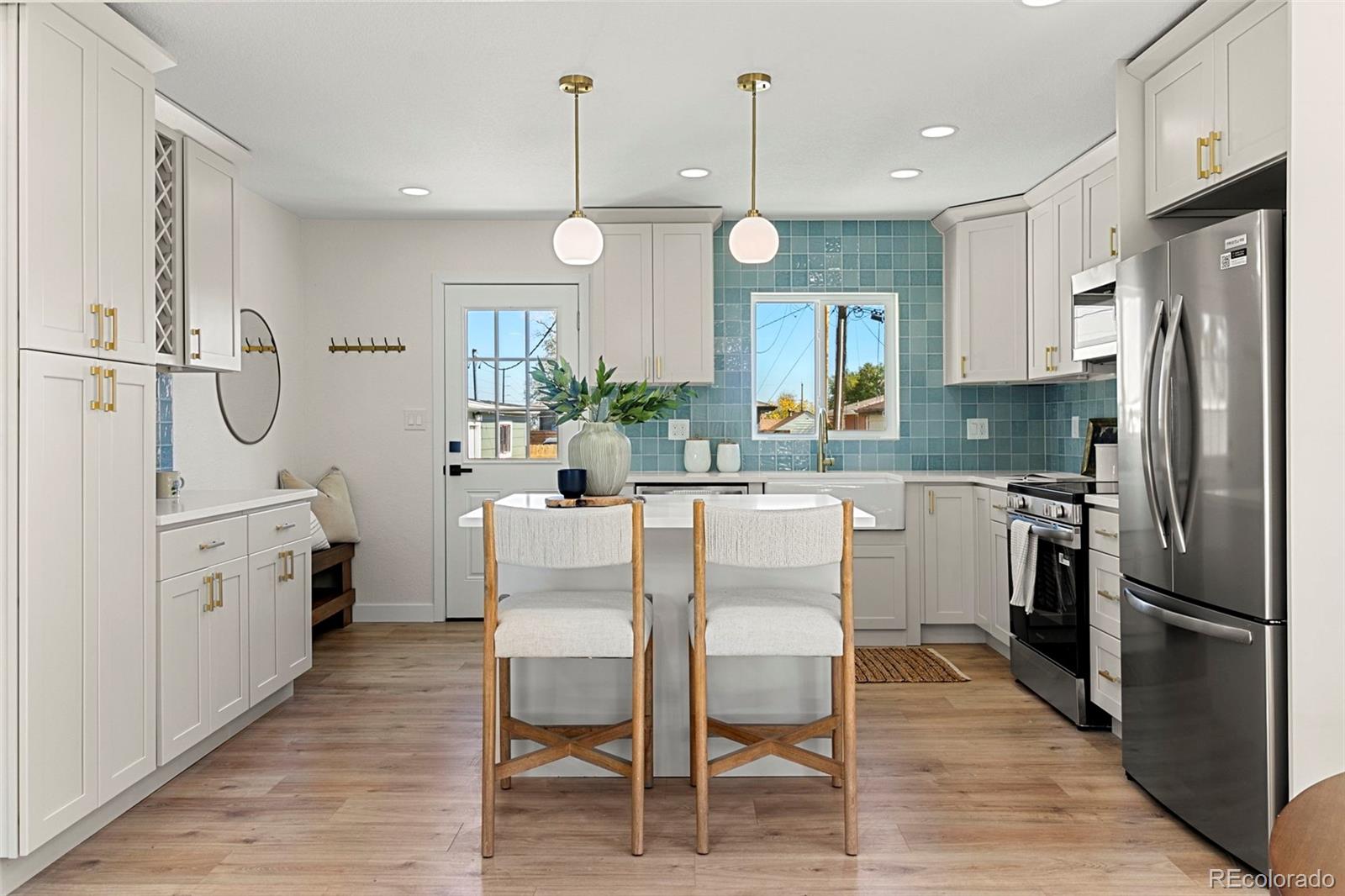 990 Tennyson Street Denver, CO 80204 - Photo 13 of 29 a kitchen with stainless steel appliances a refrigerator a sink dishwasher a stove and white cabinets with wooden floor