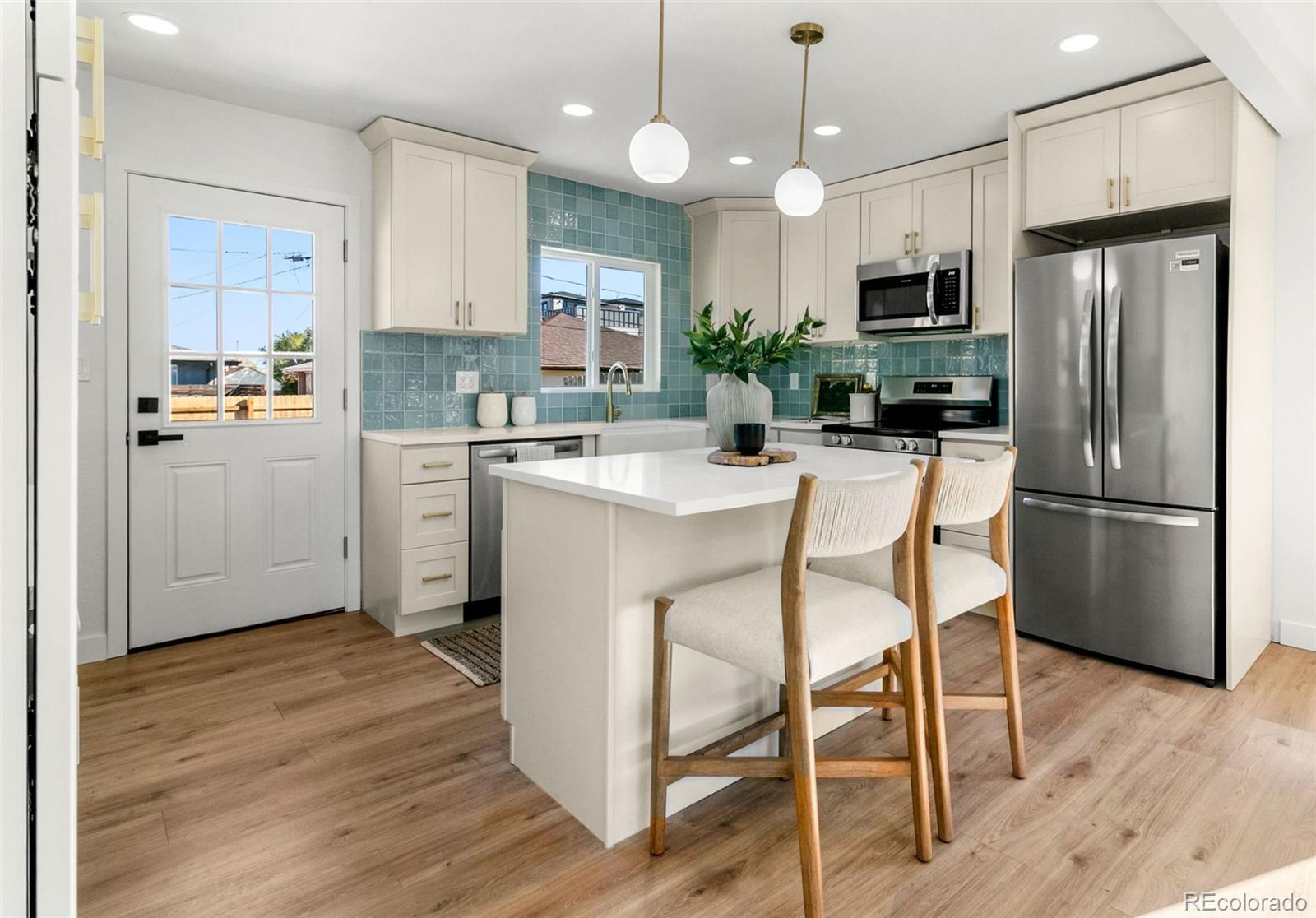 990 Tennyson Street Denver, CO 80204 - Photo 3 of 29 a kitchen with stainless steel appliances kitchen island granite countertop a refrigerator a stove a sink a dining table and chairs with wooden floor