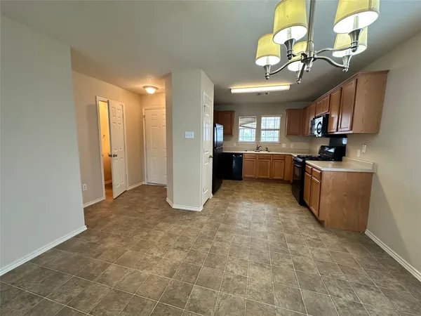 a kitchen with stainless steel appliances granite countertop a sink a stove cabinets and a dining table