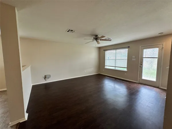 an empty room with wooden floor and windows