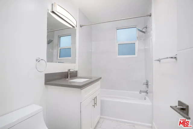 a bathroom with a granite countertop sink a toilet and shower