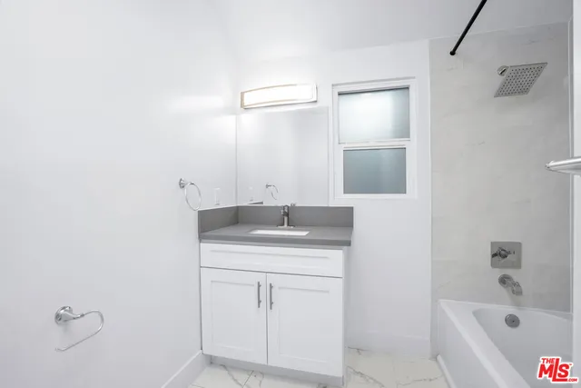 a bathroom with a bathtub sink vanity and mirror