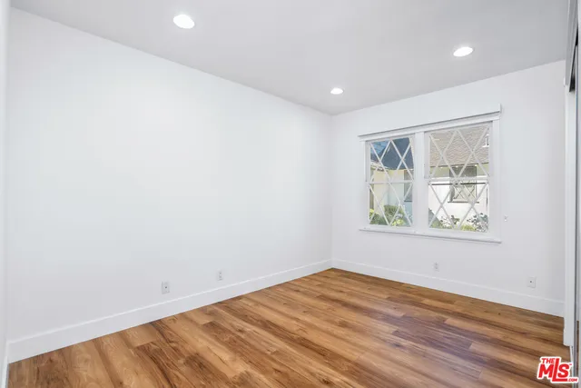 an empty room with wooden floor and window