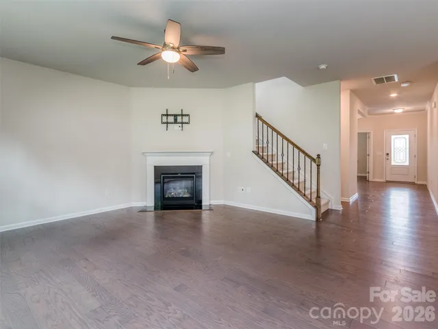 a view of an empty room with chandelier fan and a fireplace