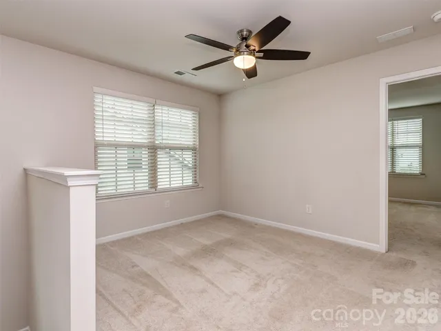 an empty room with windows and fan