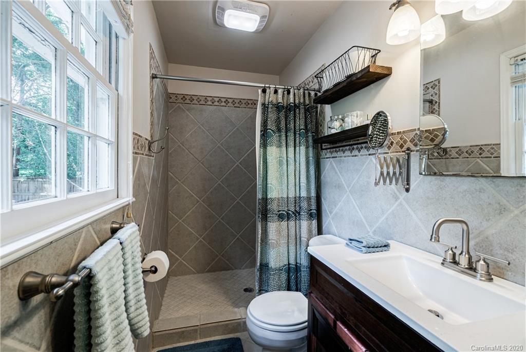 7026 Morganford Road Charlotte, NC 28211 - Photo 17 of 35 a bathroom with a sink a toilet a mirror and shower