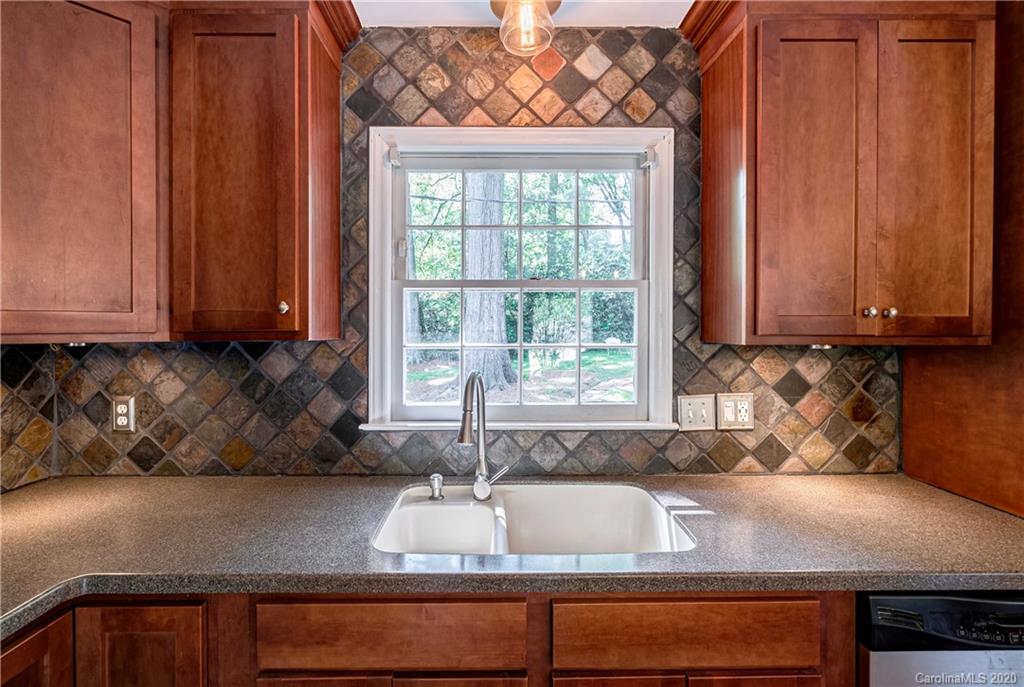 7026 Morganford Road Charlotte, NC 28211 - Photo 6 of 35 a kitchen with granite countertop wooden cabinets a sink and a window