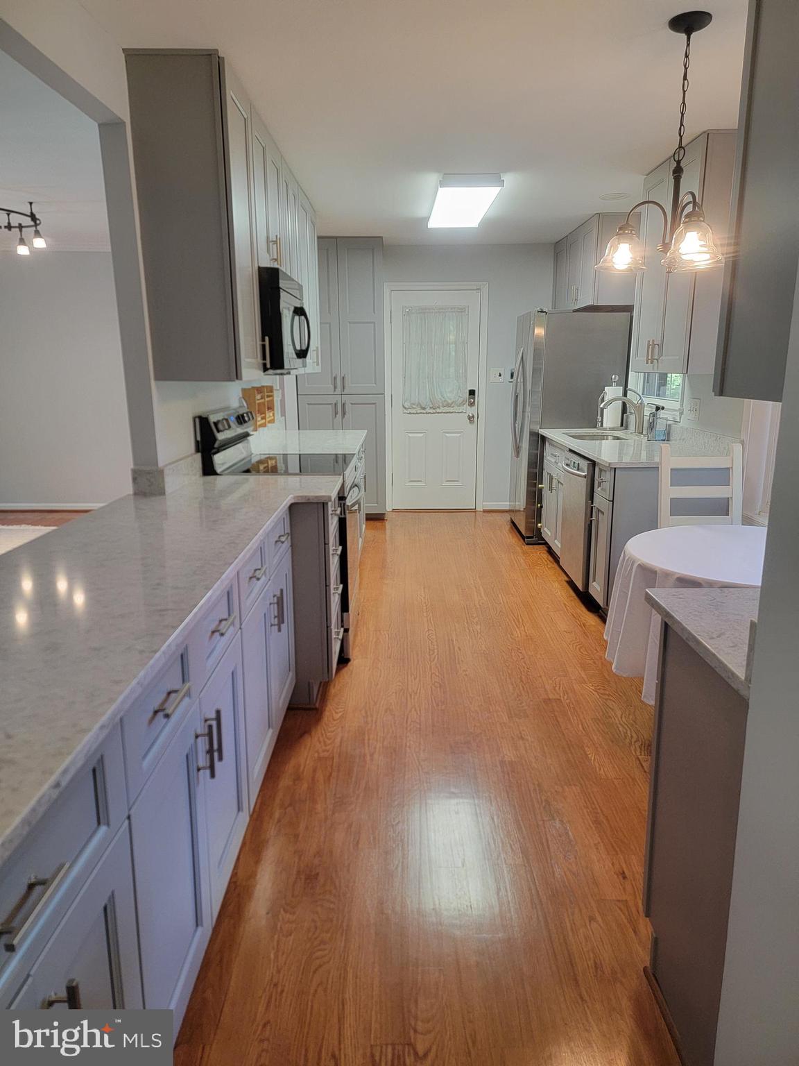 7128 Devonshire Road Alexandria, VA 22307 - Photo 11 of 36 a large kitchen with stainless steel appliances a large counter top a sink a stove a refrigerator and a wooden floor