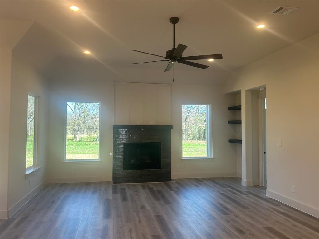 415 East Burks Street Pilot Point, TX 76258 - Photo 6 of 13 a view of an empty room with wooden floor fireplace and a window