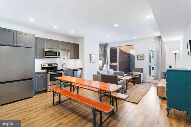 a living room with stainless steel appliances kitchen island granite countertop a couch and wooden floor