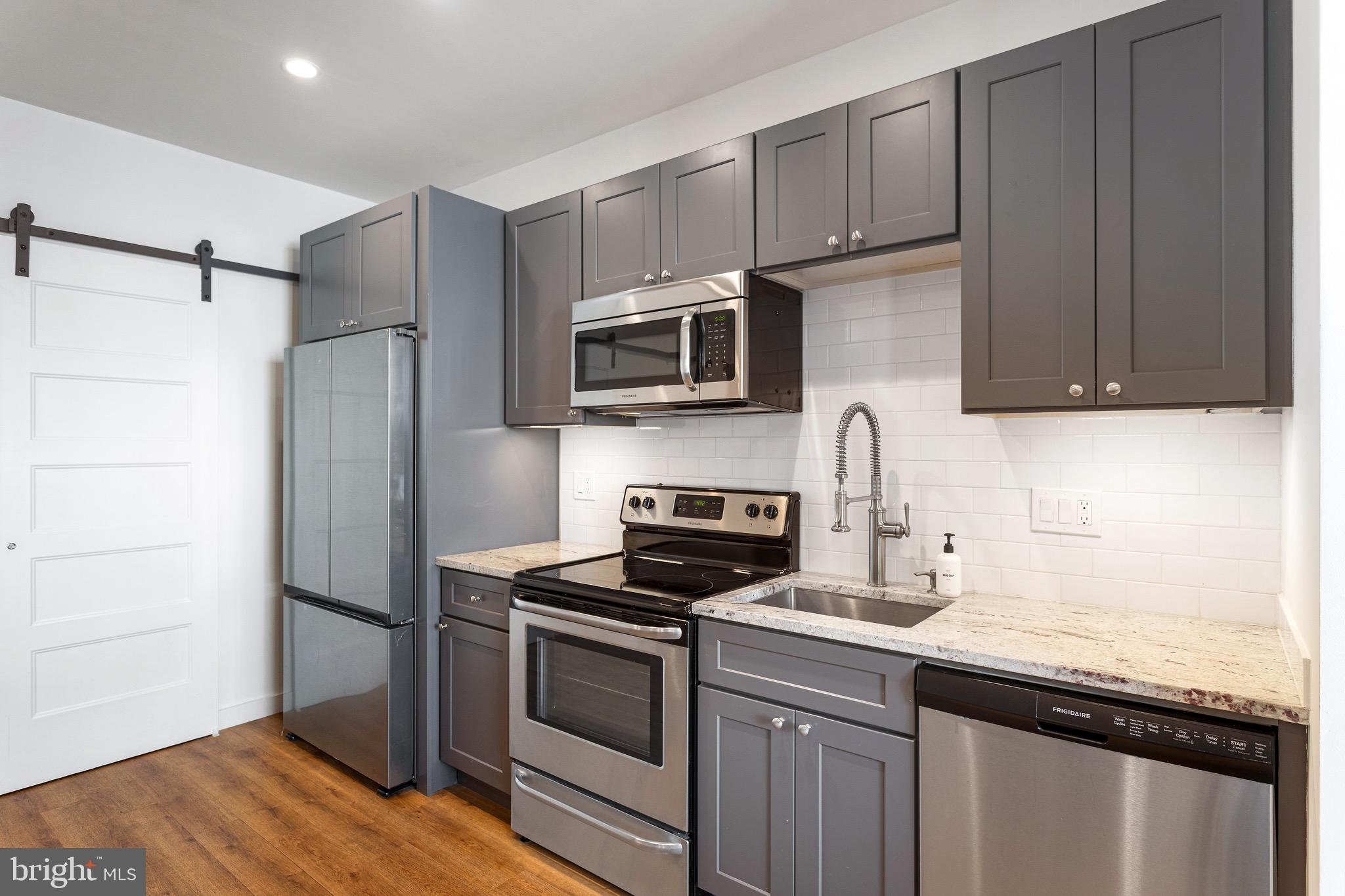 2465 18th Street Northwest, Unit 2 Washington, DC 20009 - Photo 8 of 18 a kitchen with stainless steel appliances granite countertop a stove microwave and refrigerator