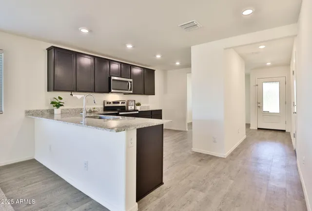 a kitchen with stainless steel appliances granite countertop a stove a sink and a refrigerator with wooden floor