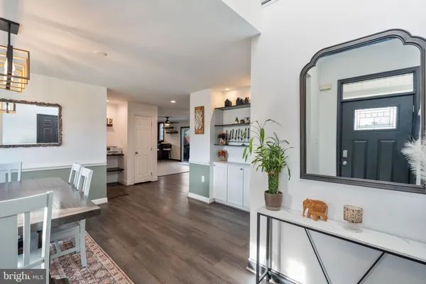 a hallway with a dining table chairs wooden floor and a flat screen tv