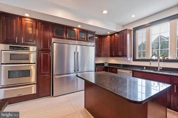 a kitchen with kitchen island granite countertop wooden cabinets a refrigerator and a sink
