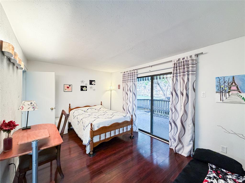4565 North O'Connor Road, Unit 1304 Irving, TX 75062 - Photo 12 of 32 Primary Bedroom featuring rich laminate flooring, a sliding glass door providing outdoor access, and a built-in wall sconce lighting fixture